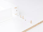 Nahaufnahme der weißen Flat-Pack-Teile mit Holzdübeln und Spanplattenkanten - perfekt für den Aufbau der KraftKids Wickelaufsatz weiß, passend für 160 cm breite HEMNES Kommode mit Blende, gerade Ausführung.
