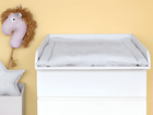 Ein KraftKids Wickelaufsatz weiß für schmale 3er/4er MALM Kommode steht an einer hellgelben Wand, mit einem weichen, gepunkteten Pad. Über dem Wickelplatz hängt ein Plüsch-Pferdekopf, daneben eine weiße Box mit Sternkissen in diesem gemütlichen Babyzimmer.