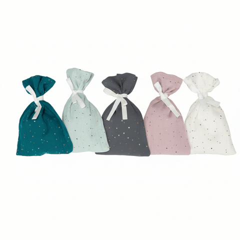 Fünf handgefertigte Musselin-Stoffsäckchen von KraftKids in Grün, Grau, Rosa und Weiß mit goldenen Punkten und weißen Bändern - perfekt als Adventskalender - sind in einer Reihe vor weißem Hintergrund arrangiert.