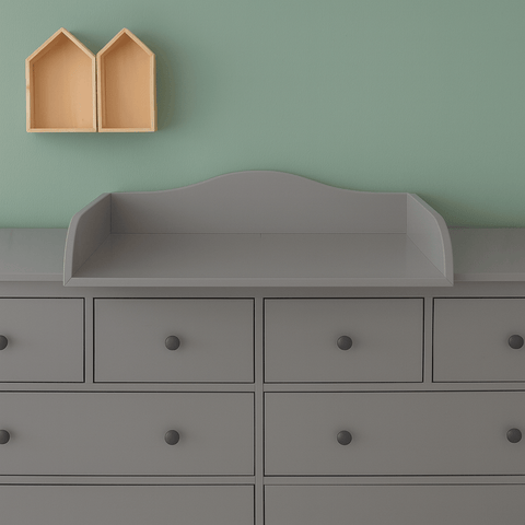 Vor einer mintgrünen Wand steht eine graue 160 cm lange HEMNES-Kommode mit dem KraftKids Wickelaufsatz grau mit Blende; darüber sind zwei gelbe, hausförmige Regale nebeneinander montiert.