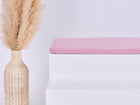 Eine hohe geflochtene Vase mit Pampasgras steht neben einem weißen Stufenpodest mit der KraftKids GmbH Sitzauflage für Ikea TROFAST Musselin rosa, alles vor einem schlichten hellen Hintergrund.