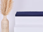 Eine hohe geflochtene Vase mit beigem Pampasgras steht neben einem weißen Stufenpodest, auf dem das KraftKids GmbH Sitzauflage für Ikea TROFAST Musselin dunkelblau Kissen liegt, vor einem schlichten hellen Hintergrund.