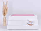 Die KraftKids GmbH Sitzauflage für Ikea TROFAST Musselin rosa verfügt über einen rosafarbenen, doppellagigen Musselinbezug mit weichem Schaumstoffkern, der perfekt zu Ihrem Regal passt. Für zusätzlichen Charme sorgt ein niedliches weißes Pferdespielzeug.