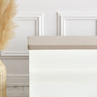 Eine weiße Bank mit der KraftKids GmbH Sitzauflage für Ikea TROFAST Musselin beige steht neben einer geflochtenen Vase mit getrocknetem Pampasgras in einem minimalistischen, modernen Raum mit weiß getäfelten Wänden.