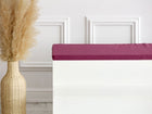 Eine große Korbvase mit Pampasgras steht neben einer weißen Bank mit der KraftKids GmbH Sitzauflage für Ikea TROFAST Leinen magenta dunkel, vor einer weißen Wand mit Zierleiste.