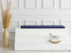 Ein minimalistisches Zimmer mit einer großen beigen Vase mit Pampasgras, einem weißen dreistufigen Podest mit dem KraftKids GmbH Sitzauflage für Ikea TROFAST Leinen blau dunkelblau Kissen und einem kleinen weißen Schaukelpferd. Im Hintergrund eine weiß getäfelte Wand.