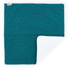 Die KraftKids Wickelunterlage Musselin goldene Punkte auf Petrol ist eine rechteckige tealfarbene Wickelunterlage mit weißen und goldenen Punkten. Eine Ecke ist gefaltet, so dass eine weiche, weiße Unterseite zum Vorschein kommt. Waschbar, wasserundurchlässig und mit einem kleinen beigen Anhänger in der linken oberen Ecke.