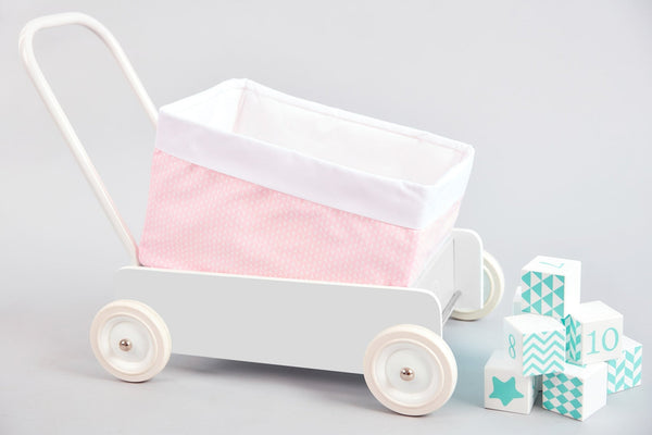 Das Körbchen kleine Blätter rosa auf Weiß von KraftKids, ein weißes Spielzeugkörbchen mit rosa blattgemustertem Stoff, wird neben pastellfarbenen Spielzeugblöcken mit Zahlen und Mustern auf hellgrauem Hintergrund gezeigt.