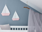 Ein weißes Kinderbett mit einem hellgrauen Baldachin steht vor einer blauen Wand, die mit KraftKids Segelboot graue Punkte auf Weiss-verspielter Kinderwanddekoration mit Polka Dots und rosa gestreiften Segeln dekoriert ist.
