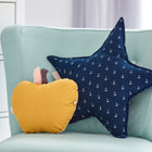 Ein hellblauer Stuhl mit einem gelben Apfelkissen und dem KraftKids Sternkissen Musselin dunkelblau Anker mit weißen Ankern steht neben einer weißen Kommode in einem hellen Kinderzimmer.