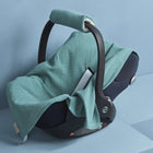 Eine schwarze Babyschale mit einer weichen, nilblauen Babydecke für Babyschale Sommer Musselin von KraftKids, die auf hellblauen Podesten vor einem hellblauen Hintergrund steht.