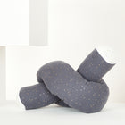 Die KraftKids Wickeltischumrandung Musselin goldene Punkte auf Grau ist ein weiches, dunkelgraues Kissen mit goldenen Punkten und weißen Akzenten, das auf einem minimalistischen weißen Hintergrund mit geometrischen Formen gezeigt wird.