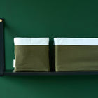 Zwei KraftKids Körbchen Doppelkrepp Grün Herbstgrün mit olivgrünen Körpern und weißen Rändern sitzen Seite an Seite auf einem eleganten schwarzen Wandregal und bieten stilvolle Aufbewahrung vor einer dunkelgrünen Wand.