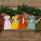 Fünf handgefertigte Stoffsäckchen von KraftKids in Herbstgrün, Gelb, Rosa und Weiß liegen nebeneinander auf Holz-ideal als wiederverwendbarer Adventskalender: Adventskalender Doppelkrepp Herbstgrün Gelb Rosa Weiß.