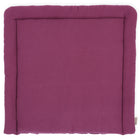 Eine rechteckige KraftKids Wickelauflage Musselin purpur in uni lila, von oben gesehen. Sie hat einen dicken gepolsterten Rand, eine glatte Oberfläche und ein kleines KraftKids-Stoffschild in einer Ecke.
