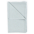 Eine sauber gefaltete KraftKids Babydecke Musselin in Grün mit goldenen Punkten und weißer Paspel auf weißem Hintergrund.