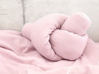 Die KraftKids Wickeltischumrandung Doppelkrepp Rosa wird mit einem Knoten gebunden und auf eine passende rosa Strukturdecke vor einem hellgrauen Betonhintergrund gelegt.