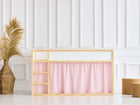 Ein minimalistisches Zimmer mit einem Bett mit Holzrahmen und KraftKids Hochbettvorhänge Set 2+1 Doppelkrepp Rosa für Kura Bett, einer geflochtenen Vase mit Pampasgras auf der linken Seite und zwei hölzernen Würfelhockern auf der rechten Seite vor einer weiß getäfelten Wand.