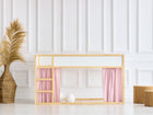 Ein minimalistisches Kinderetagenbett mit KraftKids Hochbettvorhänge Set 2+1 Doppelkrepp Rosa, für Kura Bett, steht vor einer weiß getäfelten Wand. Daneben stehen eine geflochtene Vase mit Pampasgras und zwei Holzhocker auf einem weißen Boden.