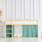 In einem minimalistischen Kinderzimmer stehen ein IKEA Kura Hochbett mit KraftKids Hochbettvorhänge Set 2+1 Musselin nilblau, eine große Vase mit Pampasgras und zwei Holzhocker auf einem hellen Holzboden in einem ruhigen, weiß getäfelten Raum.